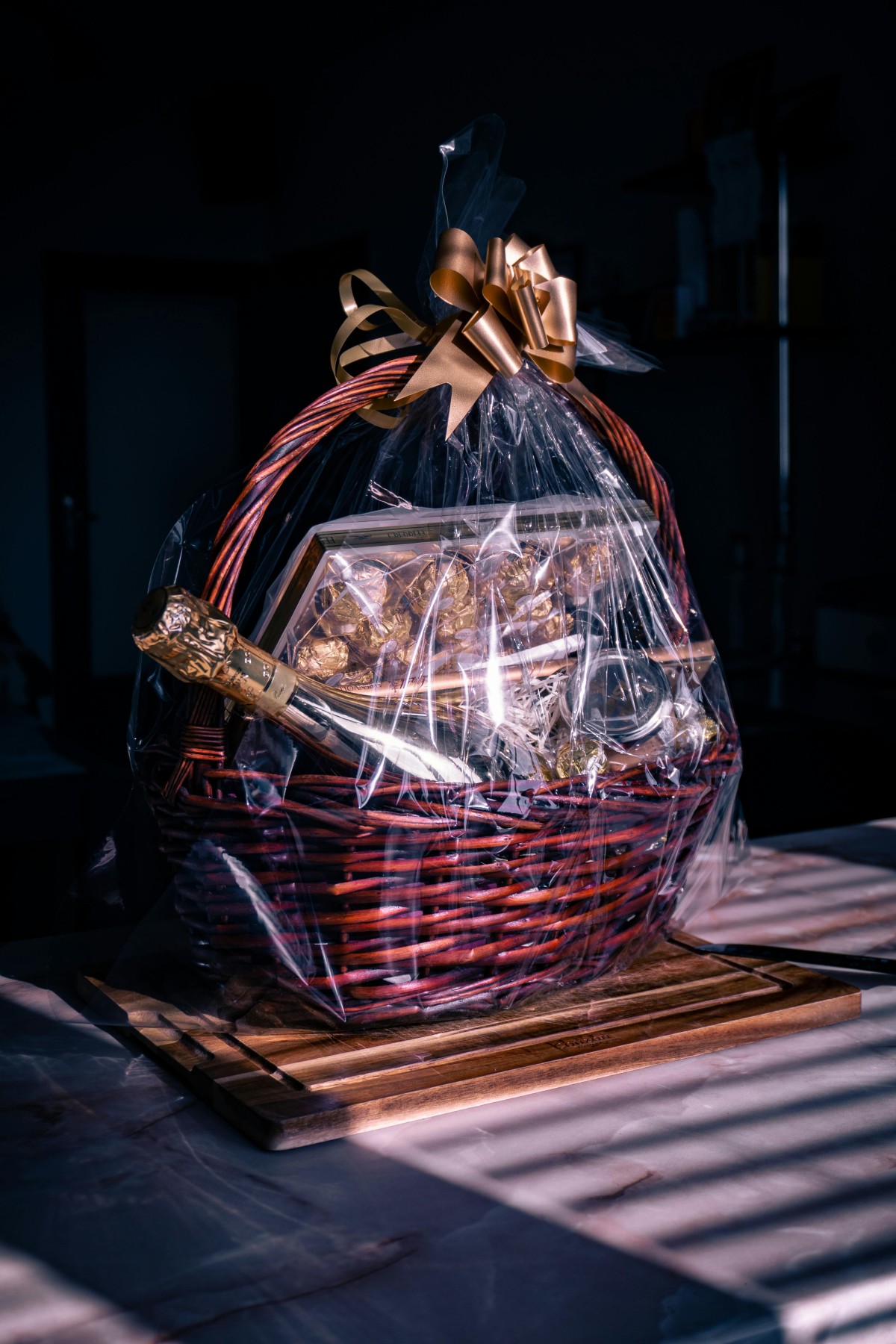 Present basket with a ribbon, champagne and chocolate sweets on a dark background by Denislav via Pexels